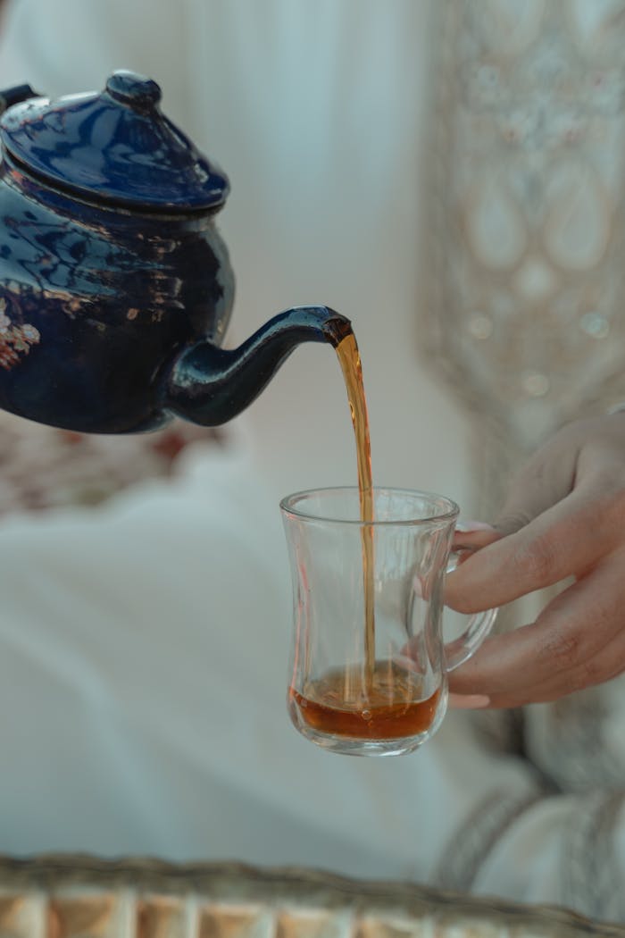 Elegant tea pouring from a teapot into a glass, highlighting Middle Eastern culture and tradition.